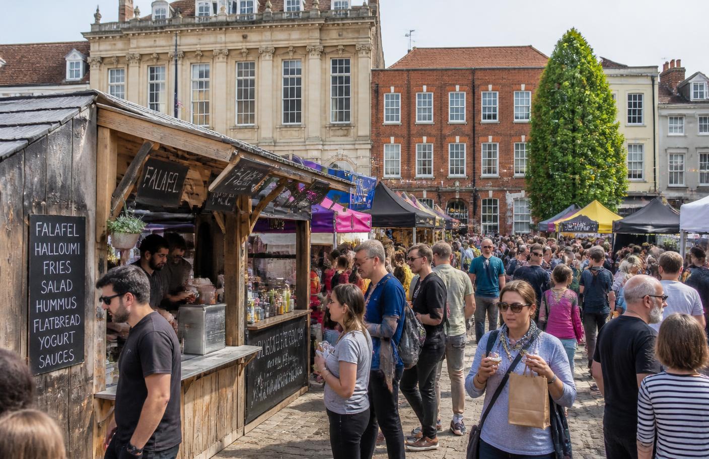 Visitors browsing wooden stalls at a busy British outdoor food market